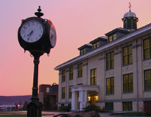Frisbie Hall and the old clock are lit up at night with a sunset
