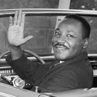 Dr. Martin Luther King, Jr waves from the front seat of a car